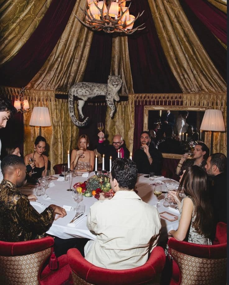 Elegant dinner party in a lavish tent featuring a taxidermy leopard and antler chandelier.